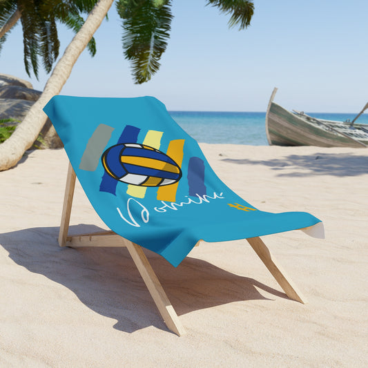 Turquoise Domino Park volleyball towel with sporty New York design, laid flat on sand.